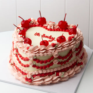 rosie design, vintage birthday cake, heart shaped, 8 inch, in pink, red, and white. with cherries on top